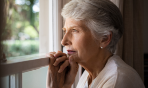 Ablakon kinéző idősebb nő