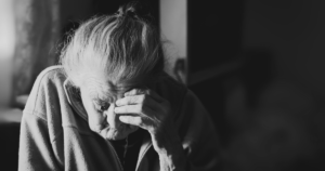 Idős, szomorúan lehajtott fejű nő