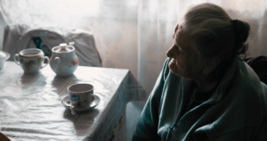 Idős nő ül egyedül egy asztalnál